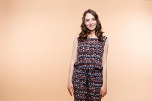 View from front of beautiful slim woman standing steady on frey isolated background. Young looking at camera, smiling and posing in studio.