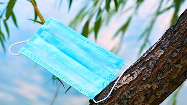 a covering for all or part of the face, worn as a disguise, or to amuse or terrify other people.Protective mask with tree green branches against the blue sky.