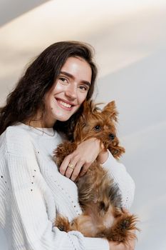 Young attractive woman with dog yorkshire terrier smiles. Close up photo. Pet care. People and pets. Girl holds brown dog isolated on white background