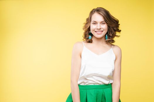 View from front of beautiful slim woman standing steady on frey isolated background. Young looking at camera, smiling and posing in studio.