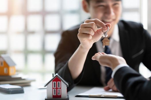 estate agent giving house keys to woman and sign agreement in office.