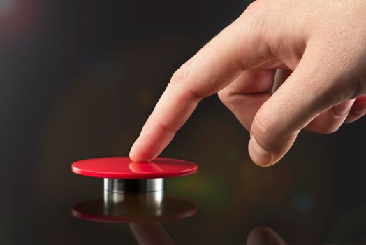 The hand presses the big red button. The concept of the threat of nuclear war. A threat to the world with a nuclear suitcase and a bomb. The hand presses the rocket launch button