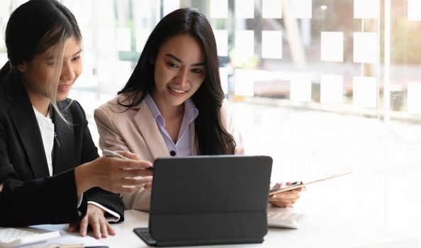 Two beautiful young asian businesswoman working together using digital tablet at office..