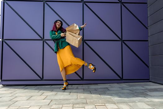 A happy shopaholic girl throws her bags near a shopping center. Have fun shopping on Black Friday. the girl in the store is happy with her purchases, throws packages. Consumer concept