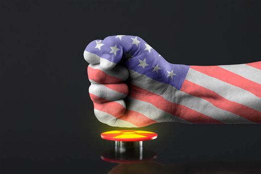 The hand presses the big red button. The concept of the threat of nuclear war. The fist is painted in the colors of the American flag, presses the button to launch a nuclear bomb