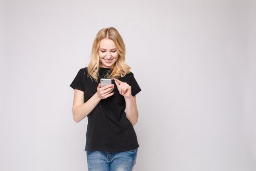 Studio portrait of beautiful caucasian brunette woman in patterned overall pointing at her smartphone with index finger. She is certain or sure about something. I know gesture.