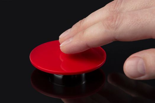 The hand presses the big red button. The concept of the threat of nuclear war. A threat to the world with a nuclear suitcase and a bomb. The hand presses the rocket launch button