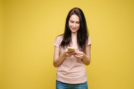 Studio portrait of beautiful caucasian brunette woman in patterned overall pointing at her smartphone with index finger. She is certain or sure about something. I know gesture.