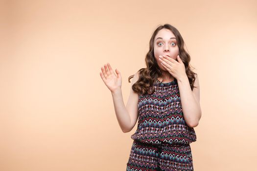 Waist up portrait of surprised beautiful girl with nice long hair, perfect makeup and fashion manicure. She is looking at camera with astonishment. Isolated on dark background