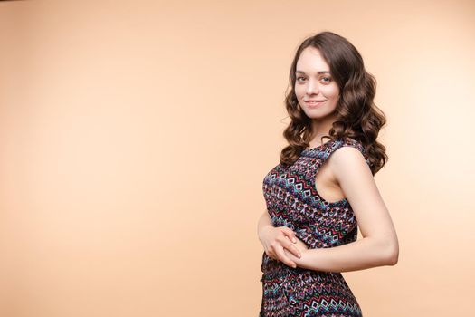 View from front of beautiful slim woman standing steady on frey isolated background. Young looking at camera, smiling and posing in studio.