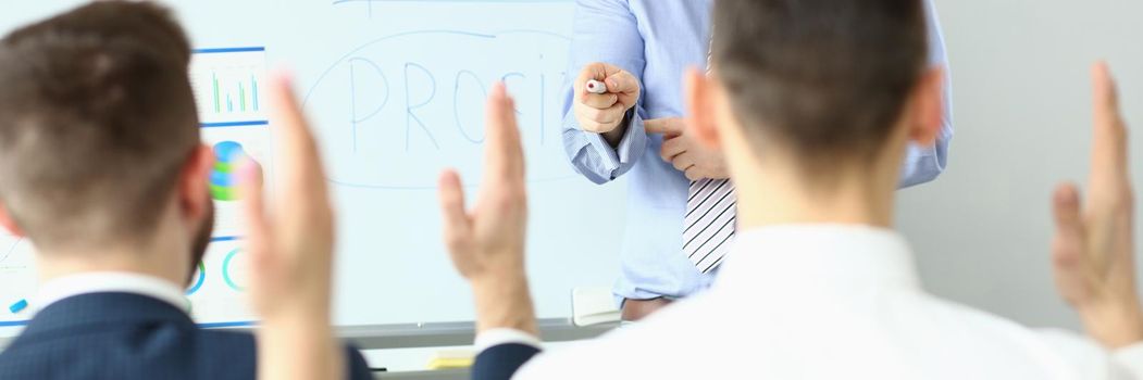 Focus on hand pointing to person wanting to ask something. Workers sitting at office in conference room. Company and business meeting concept. Blurred background