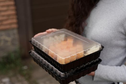 Closeup sushi set in box healthy food delivery online service. Girl holds 2 sushi sets in hands