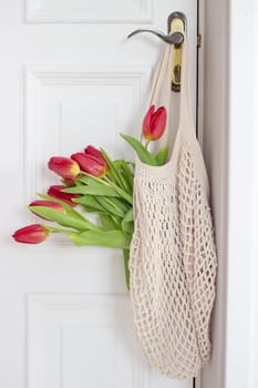 A beautiful bouquet of tulips with a string bag. Banner for the Happy Easter holiday, Woman's Day Copy space. Flat lay, top view. Spring aestetic.