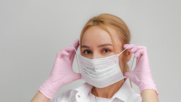 The doctor puts on a mask. Close-up portrait of medical staff. A woman in a protective mask .Isolated on a white background. Healthcare, cosmetology and medical concept.