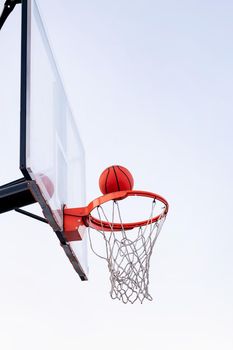ball entering in a basketball hoop with the sky in the background, concept of urban sport outdoors, copy space for text