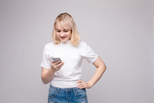 Studio portrait of beautiful caucasian brunette woman in patterned overall pointing at her smartphone with index finger. She is certain or sure about something. I know gesture.