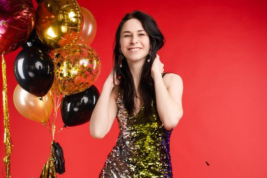 Full length studio portrait in sexy sparkling cocktail dress with red lips. She is posing with lips air balloon. Isolate on red background.