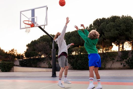 two young friends playing basketball on a city court, concept of urban sport in the street, copy space for text