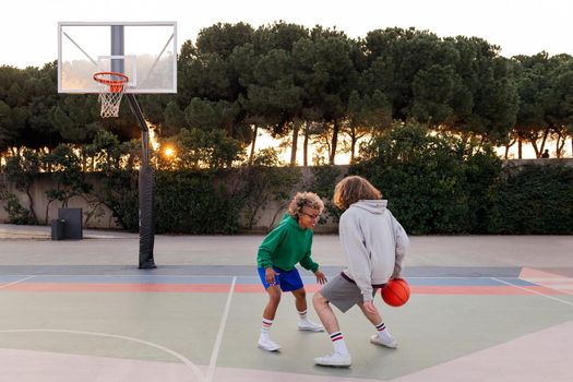 two young friends play basketball on a city court, concept of urban sport in the street, copy space for text
