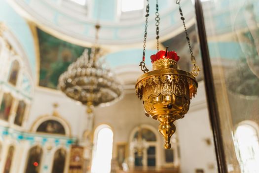 Gold censer with a red candlestick in the church. Big chandelier on the background. Church interior