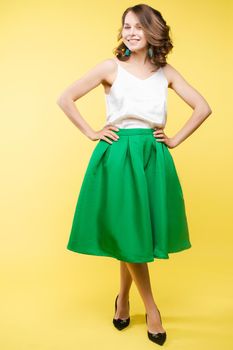 View from front of beautiful slim woman standing steady on frey isolated background. Young looking at camera, smiling and posing in studio.