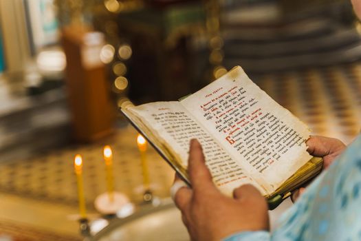 Holy book opened in priest hands in church. Priest reads pray. Orthodox faith. Equipment for praying. Pray for people life. Pray to god