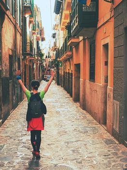 Woman backpacker walk by old street in the old town of Palma de Mallorca city, Spain. 29th of January 2020