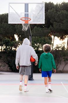 rear view of latin woman and caucasian man chatting walking down the court after basketball practice, concept of friendship and urban sport in the street, copy space for text