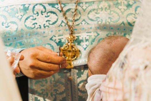 Hair cutting in a church for a year old child. Holy father cuts the hair of a baby. Orthodox tradition and faith. Equipment for praying