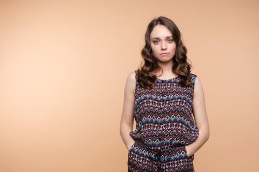 Upset young beautiful woman standing with crossed hands isolated at white studio background medium long shot. Unhappy European female looking down having negative emotion