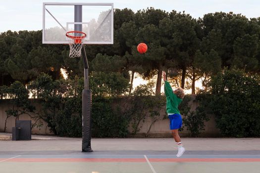 unrecognizable young latin woman shooting baskets in a city park court, concept of urban sport outdoors