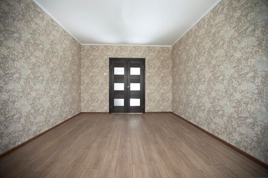 Empty room with laminate floors beige walls in the background