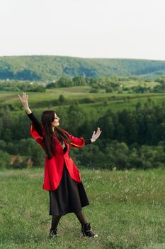 Georgian girl dances national dance in red national dress on the green hills of Georgia background. Georgian culture lifestyle.