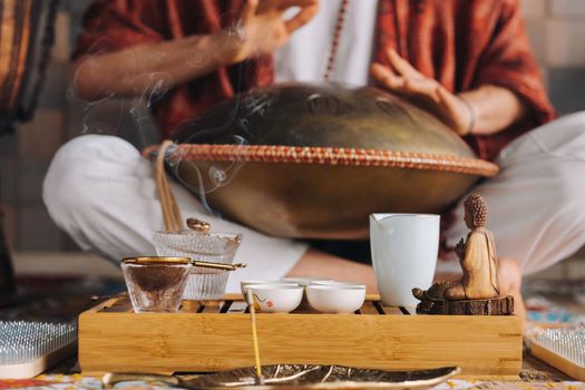 Close-up of a man's hand playing a modern musical instrument - the Orion tongue drum during the tea ceremony.