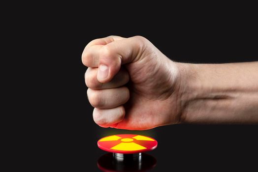 The hand presses the big red button. The concept of the threat of nuclear war. A threat to the world with a nuclear suitcase and a bomb. The hand presses the rocket launch button
