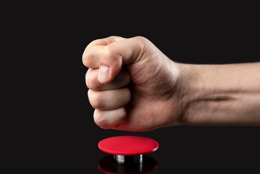 A man's hand presses a big red button. Red button on a dark background. The threat of using nuclear or chemical weapons of mass destruction. Rocket launch at the push of a button.