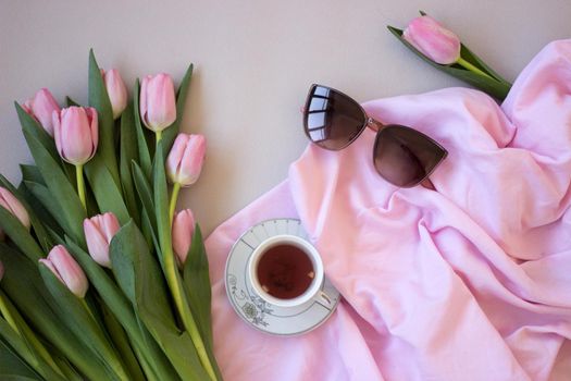 Pink tulips on wooden background. Open book, craft gift box and coffee. Mothers Day, Women Day, floral desing, blogger table and spring concept, copy space, top view.