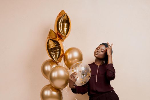 Muslim new year party with golden balloons for black woman. African attractive girl celebration of the end of year. Happy emotion