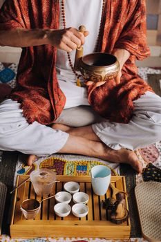 Tibetan singing bowl in the hands of a man during a tea ceremony.