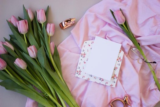 Pink tulips on wooden background. Open book, craft gift box and coffee. Mothers Day, Women Day, floral desing, blogger table and spring concept, copy space, top view.