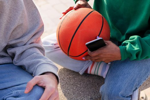 detail of a woman's hands holding a basketball and smart phone, concept of sport and modern lifestyle