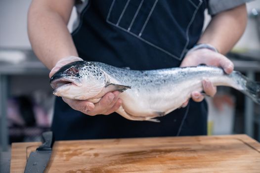 Chef with a salmon fish at the kitchen