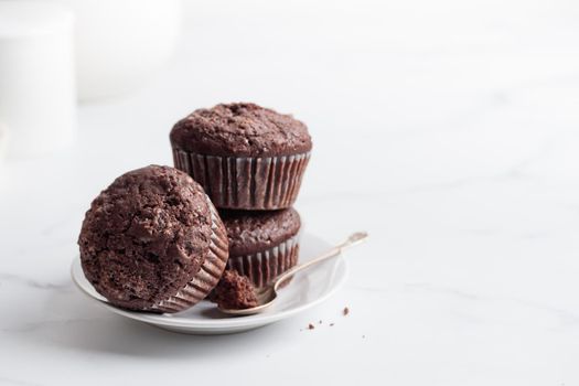 Chocolate muffins on a small white plate on a white table