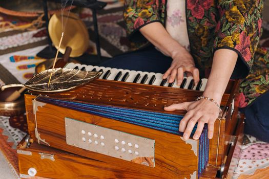 Hands of a woman sitting on the floor and playing the harmonium during the practice of kundalini yoga.