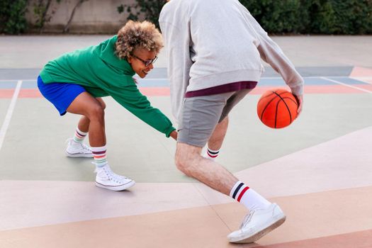 young latin woman playing basketball with her friend on a city court, concept of urban sport in the street