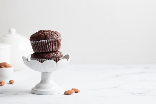 Chocolate muffins in a white cake stand on a white table