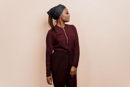 Muslim black girl looks right side. African woman weared in national dress and scarf isolated on peach background