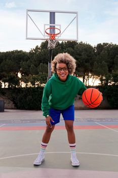 smiling latin woman playing on the basketball court in a city park, concept of urban sport in the street, copy space for text