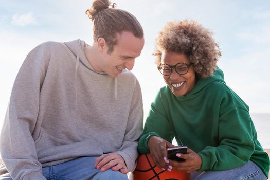 couple of young friends laughing while looking at mobile phone, concept of lifestyle and technology of communication