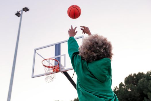 unrecognizable woman throwing a ball into a basketball hoop, concept of urban sport in the street, copy space for text